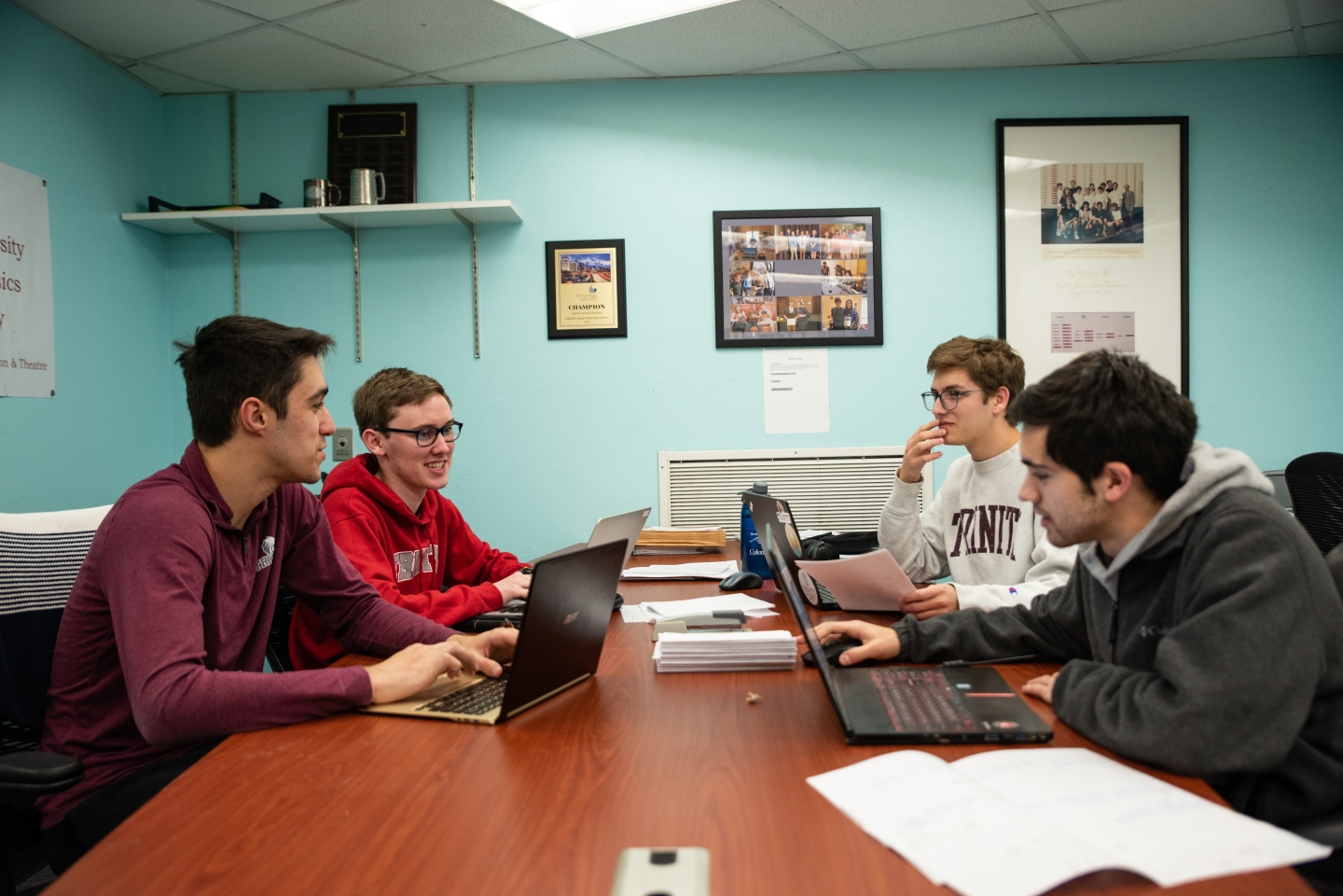 Group of students meeting around a desk with their laptops open
