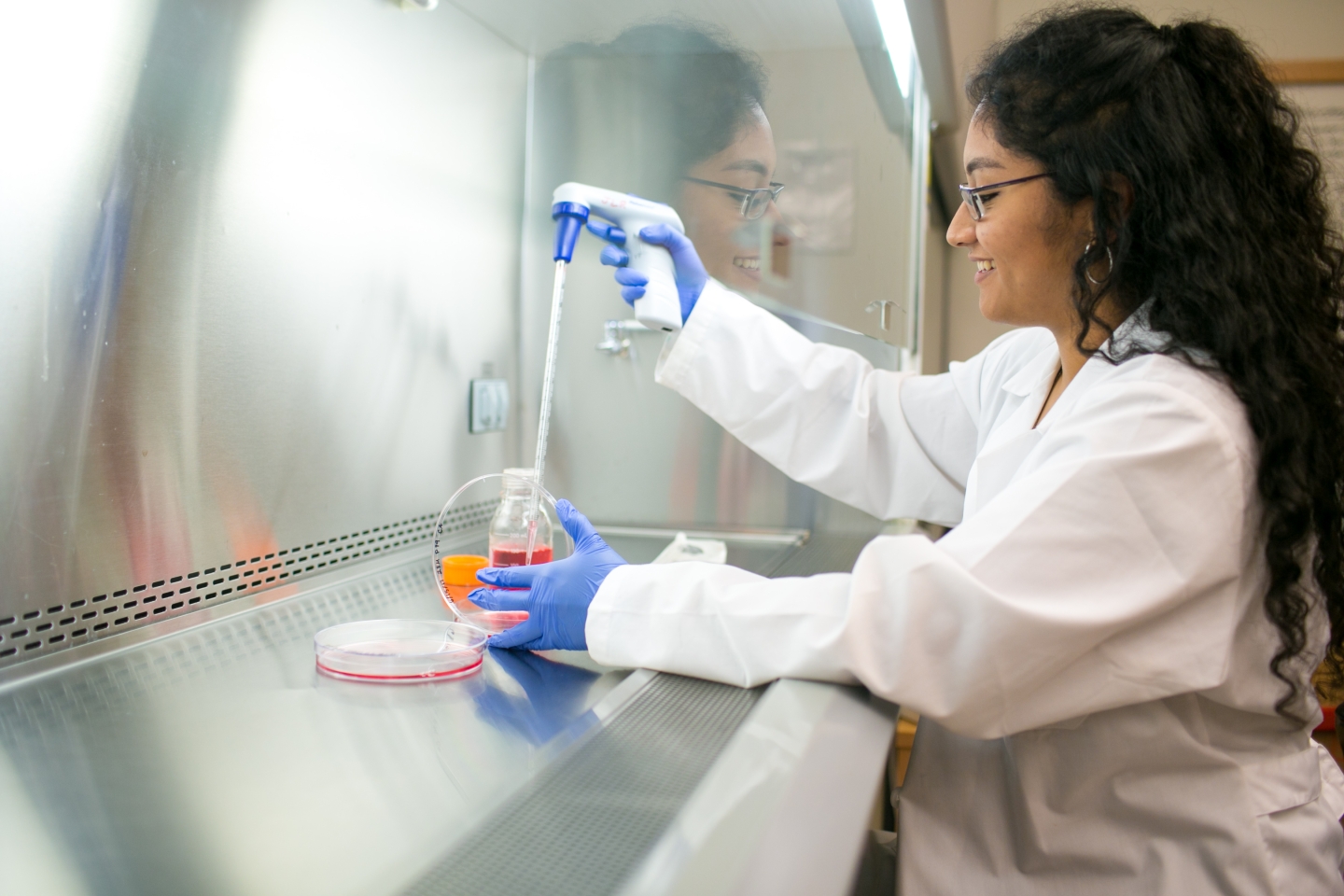 Woman taking samples from dish in a lab.