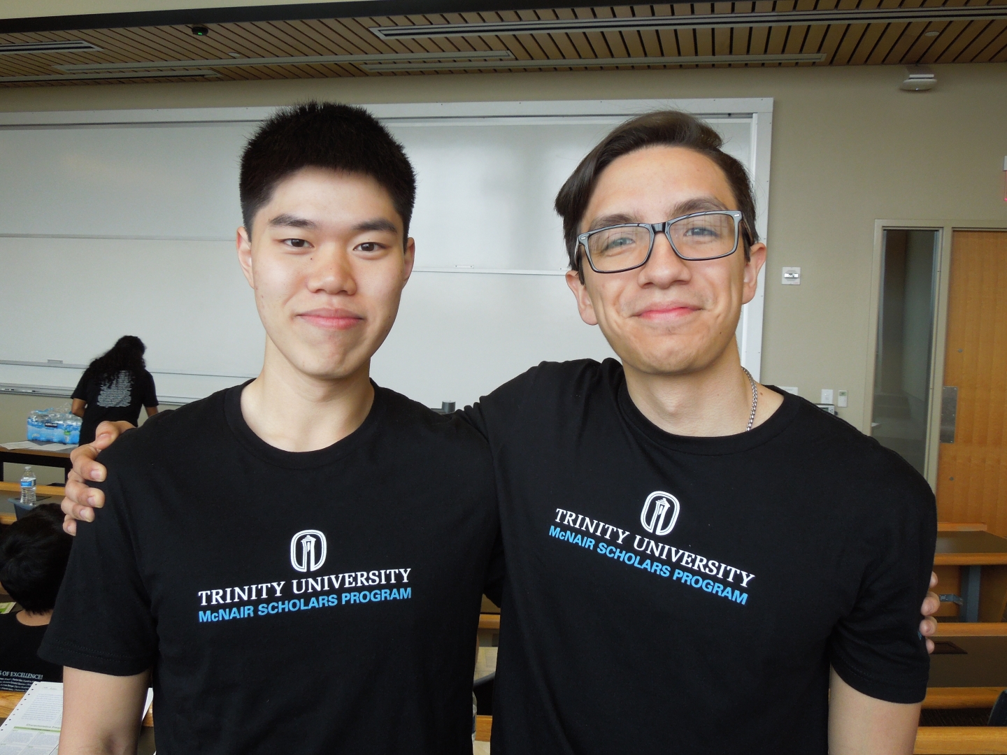 two students posing in front of a white board