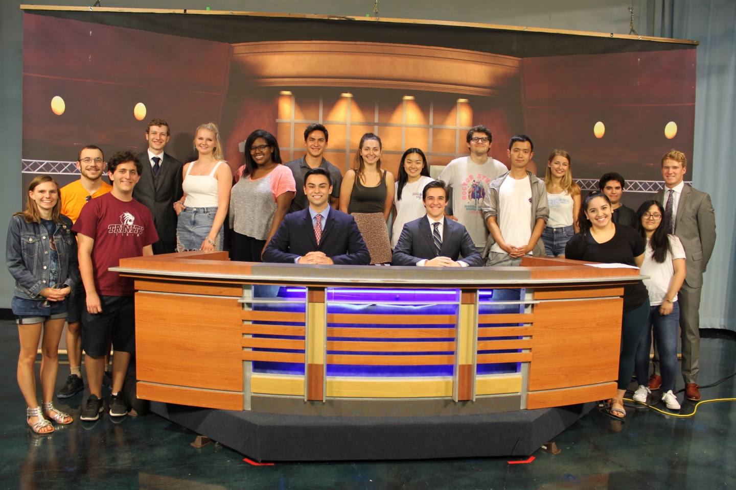 Newswave crew poses behind an anchor desk 