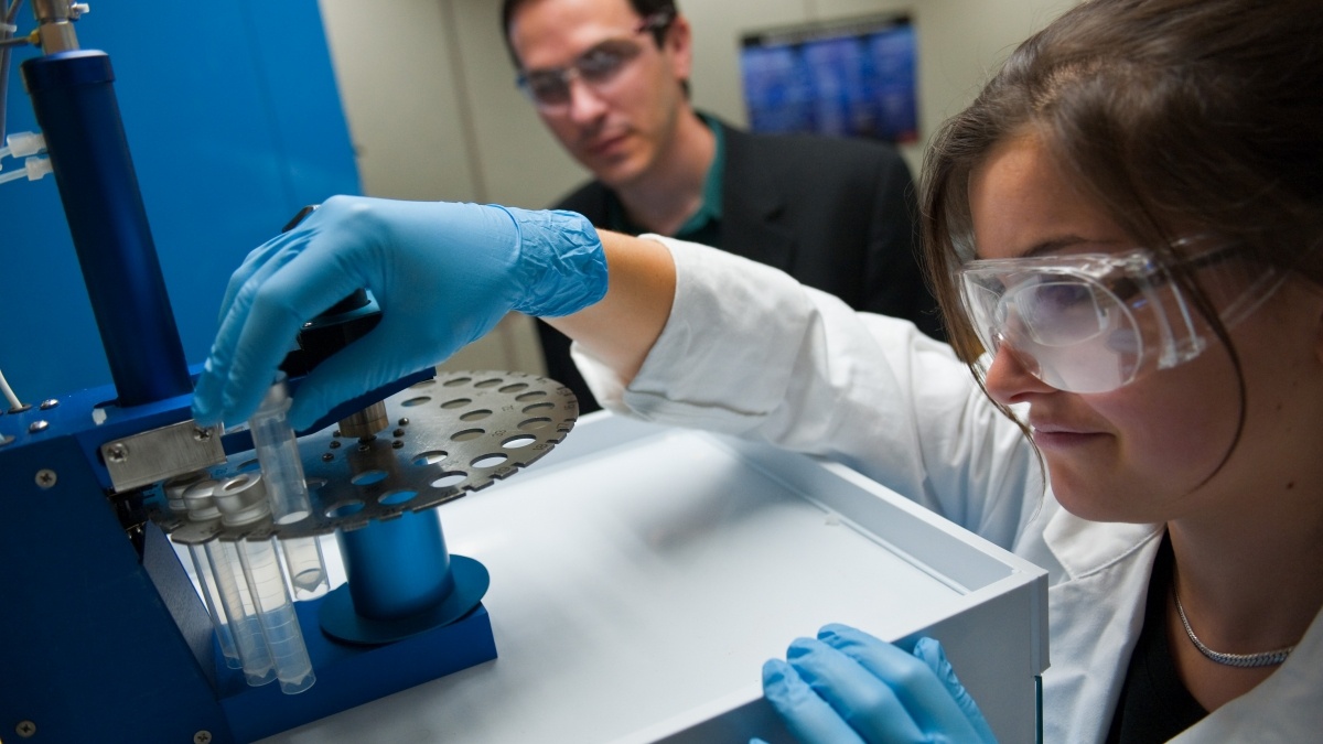 Student working with a test tube as professor observes