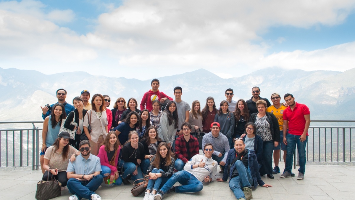 A large group of students gather with a mountain landscape in the distance