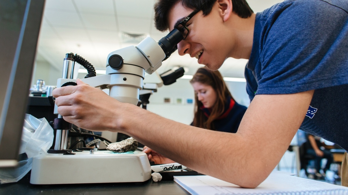 Student looking at rock through a microscope