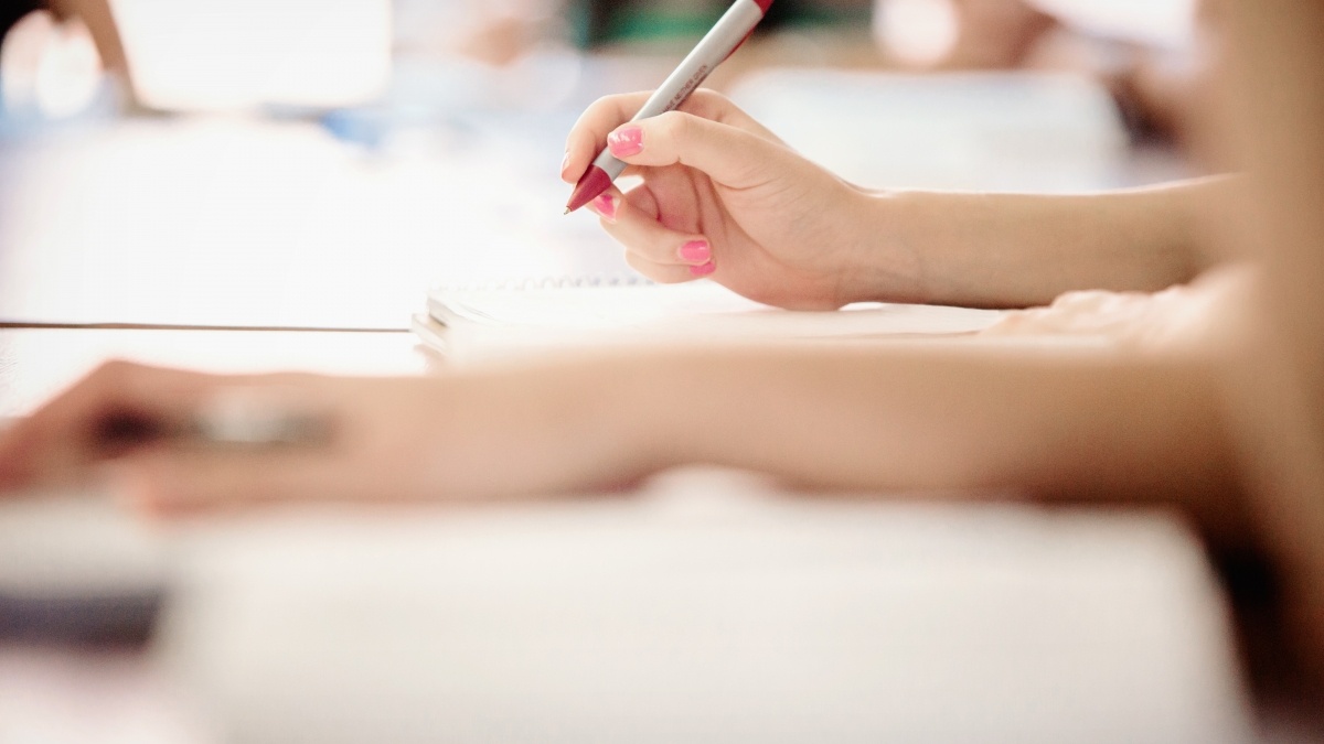 Close up of people writing in notebooks