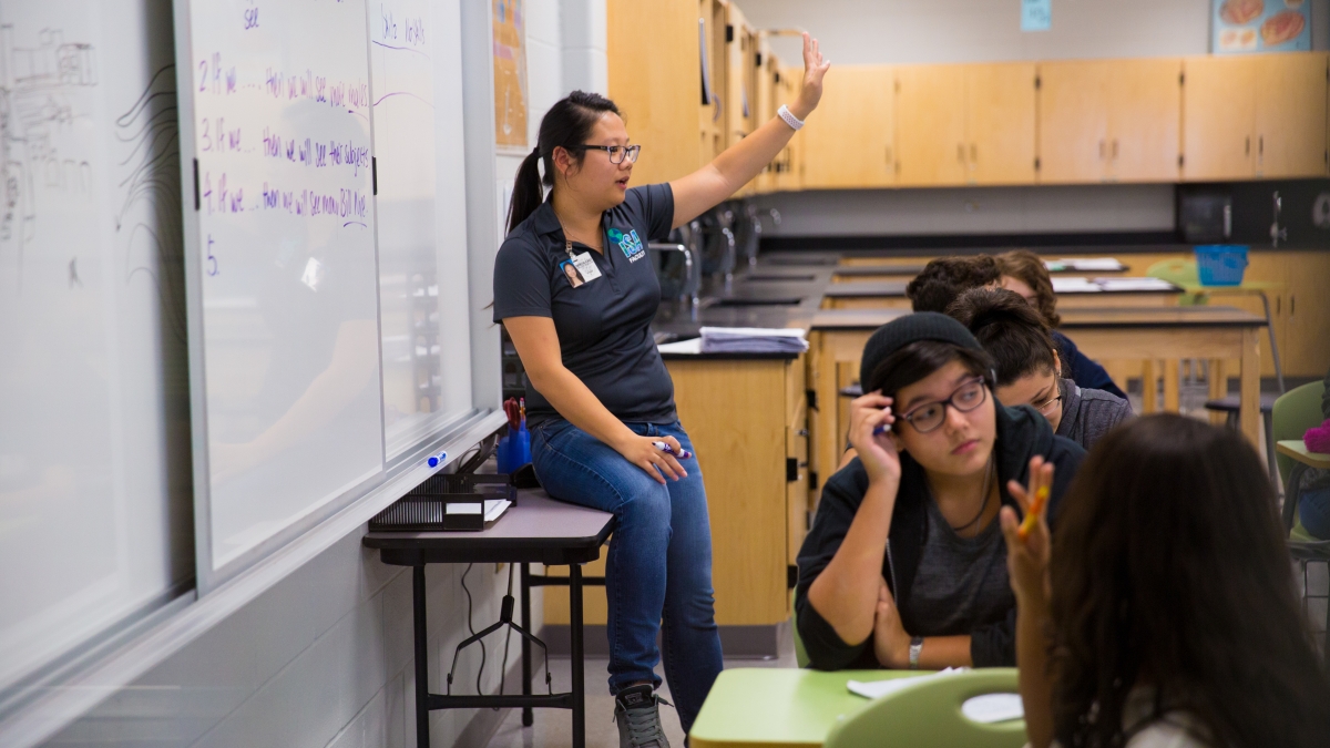 Trinity student teaching a high school classroom, while standing at whiteboard