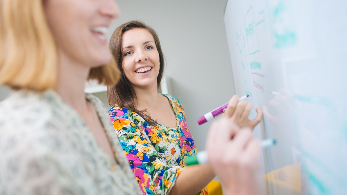 Trinity students writing on a white board. 