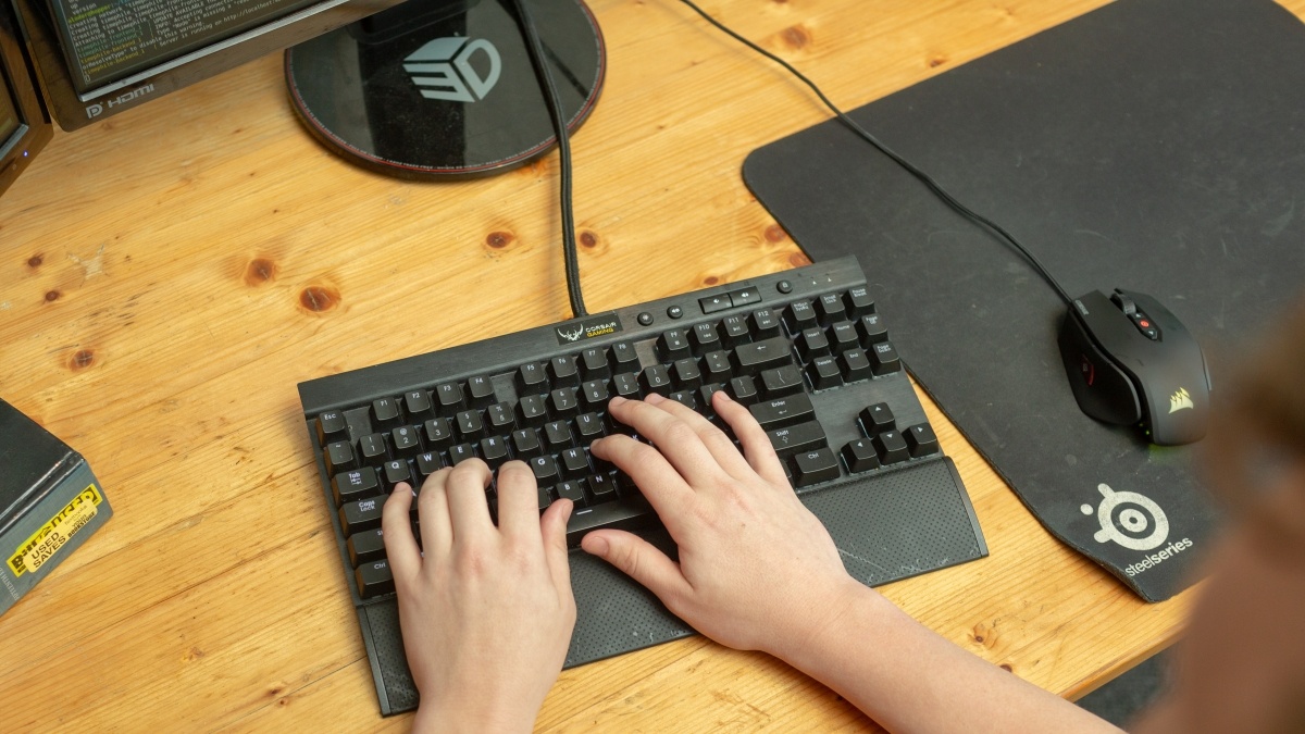 Student typing on a keyboard; code is displayed the computer screen. 