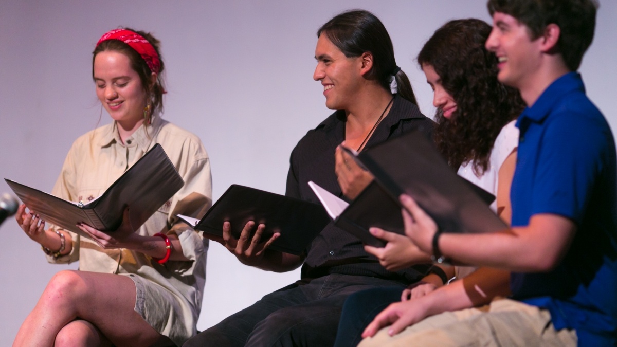 Students sitting in a circle reading scripts.