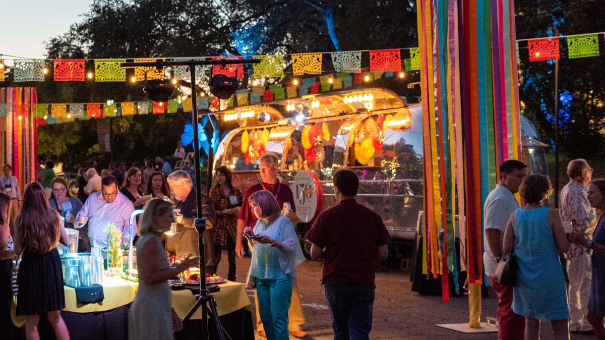 a large gathering of alumni party under papel picado on Oakmont Court in the evening